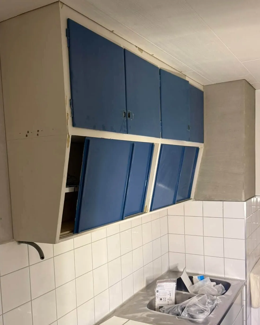 Köket före: överskåp med blå luckor ovanför vitt kakel